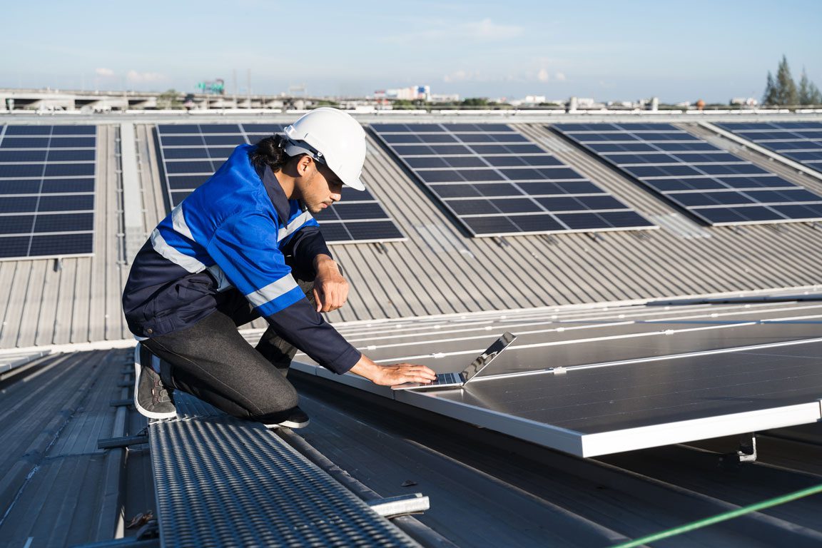 construction worker on roof with solar panels and laptop