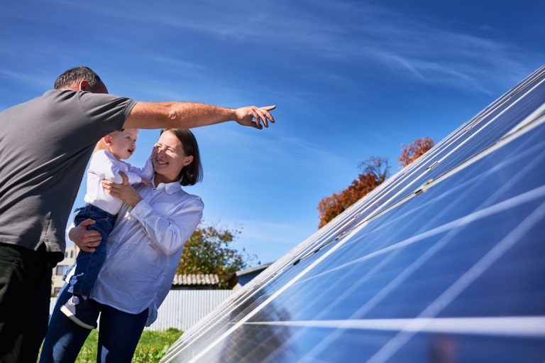 family smiling in front of solar panels